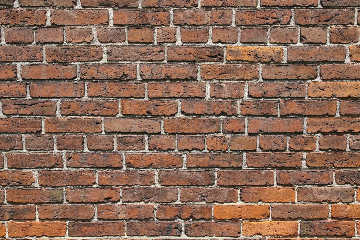 Oude bakstenen muur met uitgesleten, lichte voegen