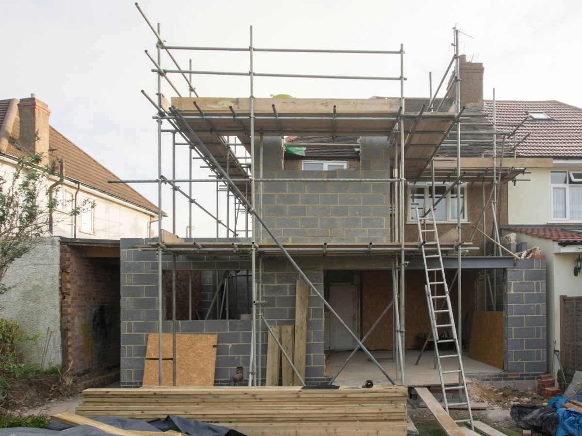 Aanbouw in snelbouwblokken met een stelling, achter een rijwoning